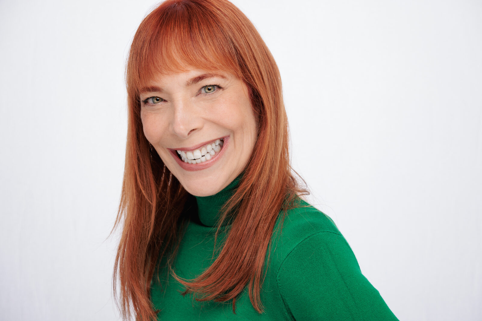 Actor headshot of Nicole in a green turtleneck, laughing