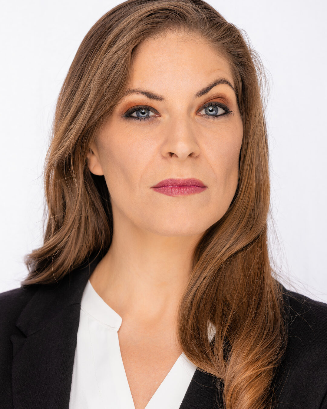 Cat as a serious executive in a black blazer and white blouse, level direct gaze